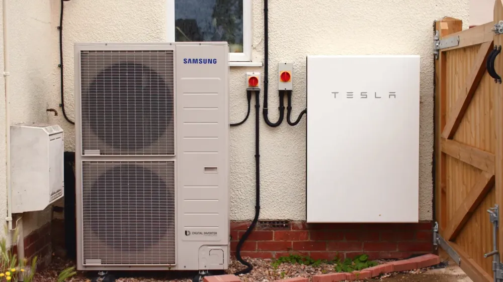 Eine Samsung-Wärmepumpe und ein Tesla-Batterienspeicher an einer Hauswand.