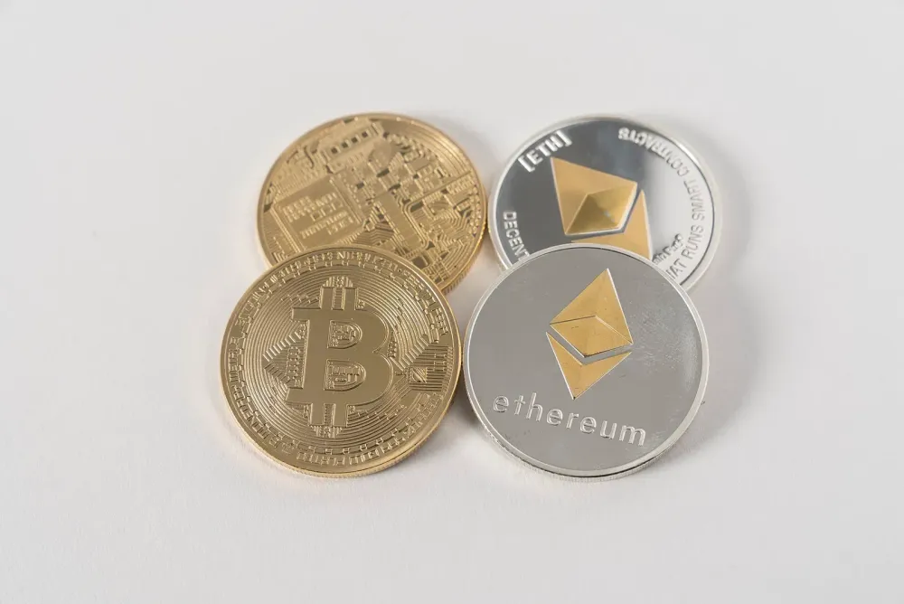 Four physical cryptocurrency coins representing Bitcoin and Ethereum on a plain white background.