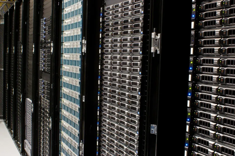Rows of black server racks filled with stacked computer hardware in a data center.