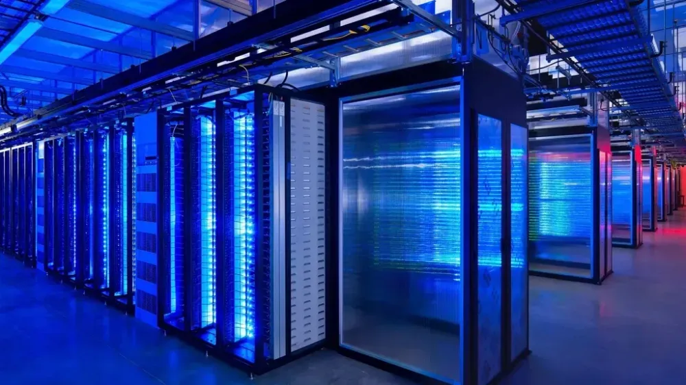 Rows of computer server racks in a data center illuminated by bright blue lights.