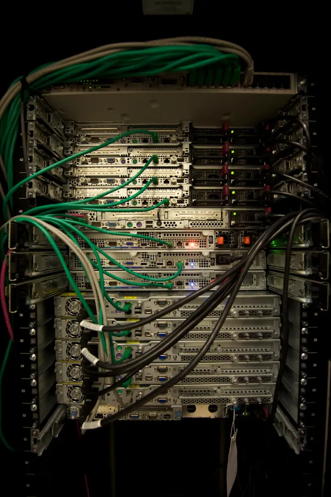 A server rack filled with computer hardware and numerous green and grey network cables.