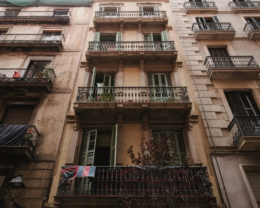 Low-angle view of traditional multi-story apartment buildings with balconies and green shutters.