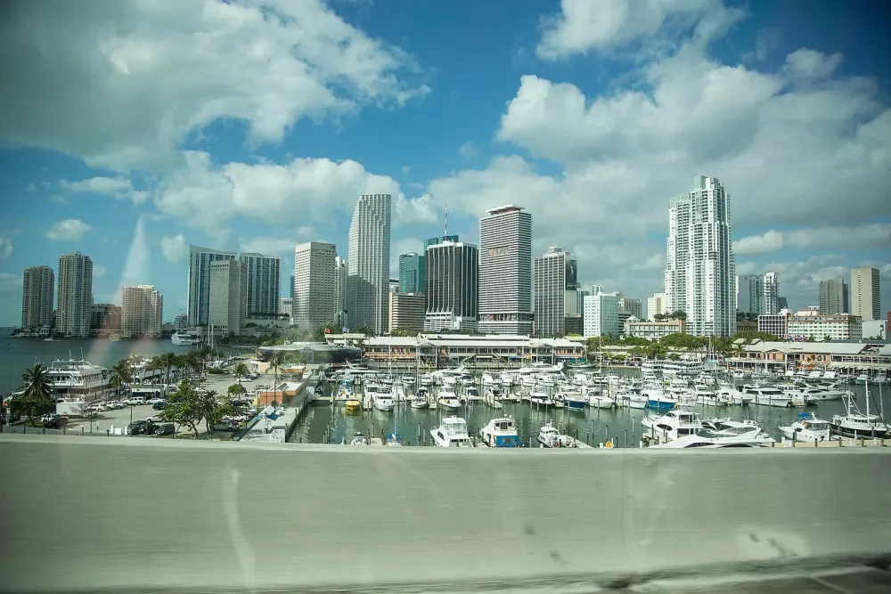 Panoramic daytime view of the Miami skyline and a marina filled with boats.