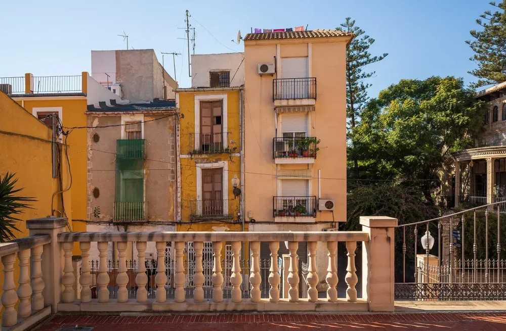 Colorful townhouses viewed past a stone balcony railing.