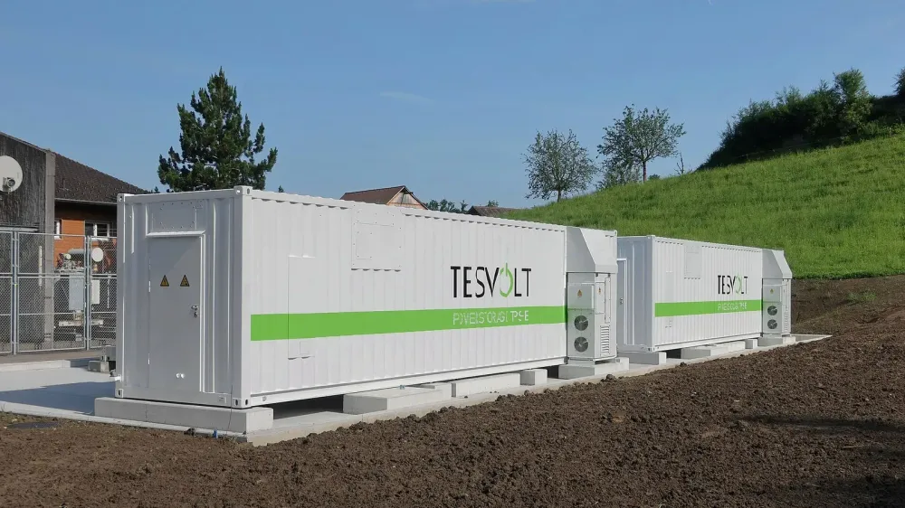 Zwei weiße Energiespeicher-Container im Außenbereich auf Betonfundamenten.