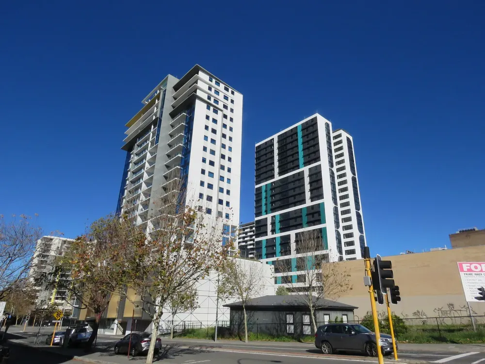 Two tall modern residential towers under a blue sky.